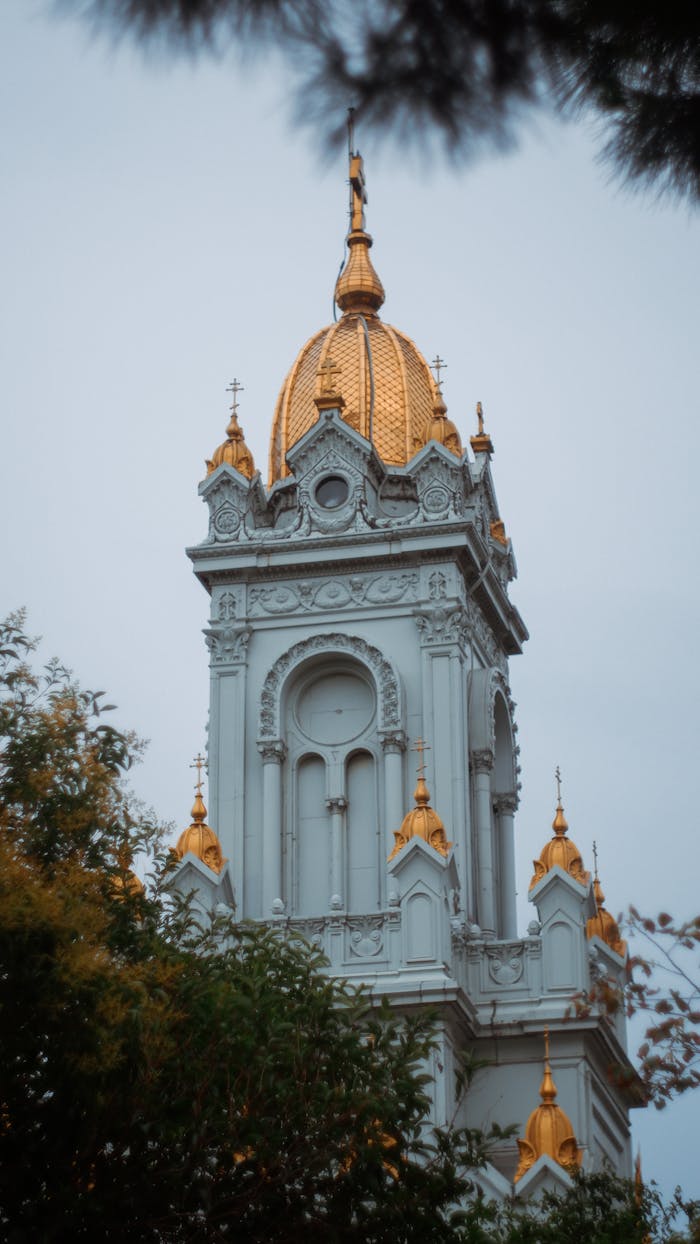 Elegant vertical shot of the Bulgarian St. Stephen Church tower in Istanbul, showcasing its intricate design and golden details.